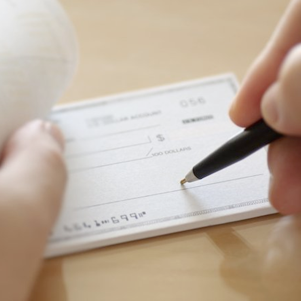 MCLose up of a man writing a check